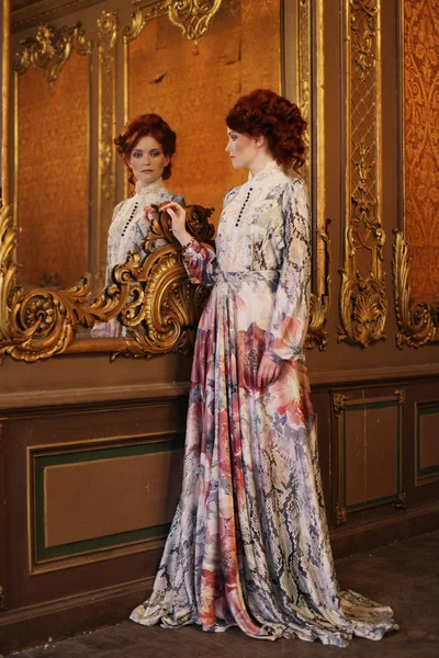 Mooie vrouw staan in de paleis kamer met spiegel. — Stockfoto