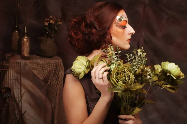 Mulher com brilhante criativo compõem segurando flores verdes — Fotografia de Stock