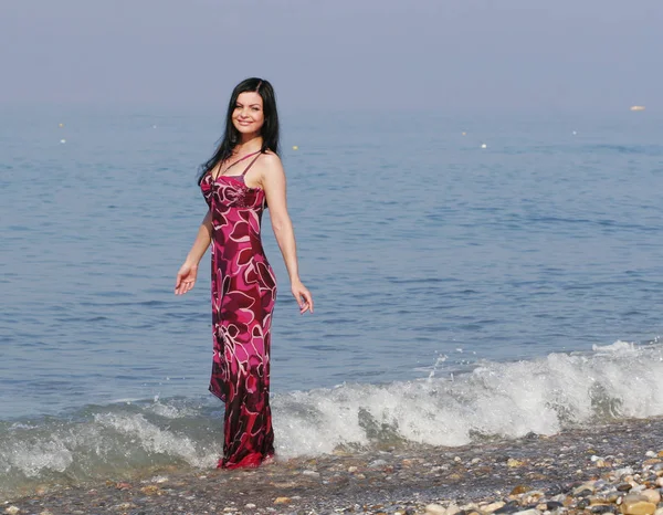Kvinna i rosa klänning på havsstranden — Stockfoto
