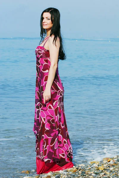 Frau im rosa Kleid am Meeresstrand — Stockfoto