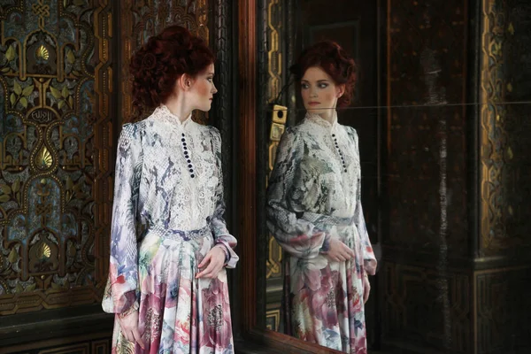 Mooie vrouw staan in de paleis kamer met spiegel. — Stockfoto