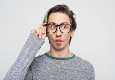  Sarı kazak giyen çekici bir adam şaşkınlık ve şaşkınlık içinde şaşırdı ve şaşırdı.