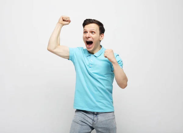 Fiatal férfi ünnepli győzelem fehér háttér — Stock Fotó