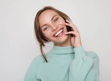  Güzel, neşeli bir kadın cep telefonuyla konuşuyor.