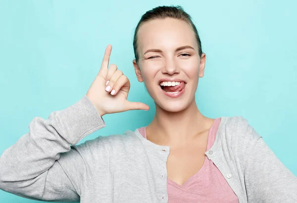 Menina engraçada mostrando sua língua enquanto posando contra o fundo do estúdio. Emocional positivo jovem fêmea fazendo rostos — Fotografia de Stock