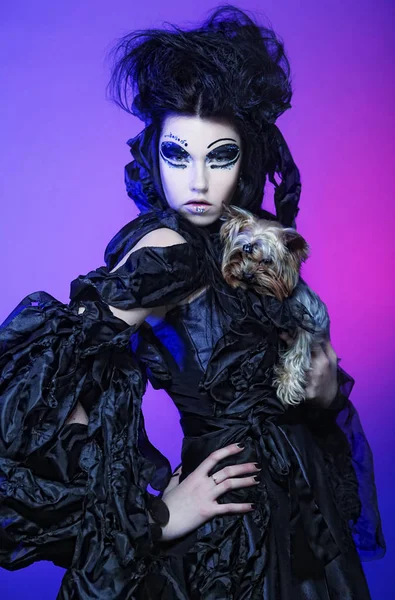 어두운 배경 위에 작은 강아지와 함께 우아한 어두운 여왕 — 스톡 사진