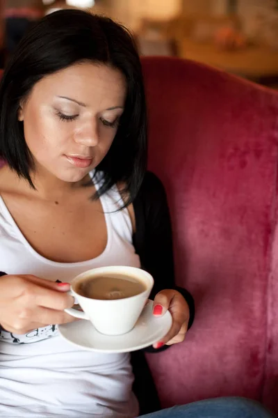 Jovem mulher sentada em um café bebendo café — Fotografia de Stock