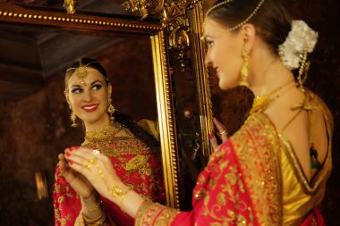Evdeki güzel Hintli kızın gülümseyen portresi. Altın mücevherleri olan genç bir kadın model. .