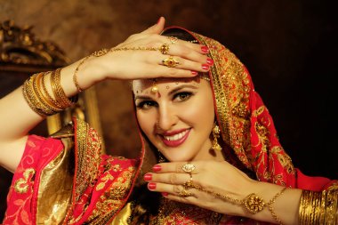 Evdeki güzel Hintli kızın gülümseyen portresi. Altın mücevherleri olan genç bir kadın model. .