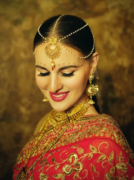 Retrato sonriente de hermosa chica india en casa. Modelo de mujer joven con conjunto de joyas de oro . — Foto de Stock