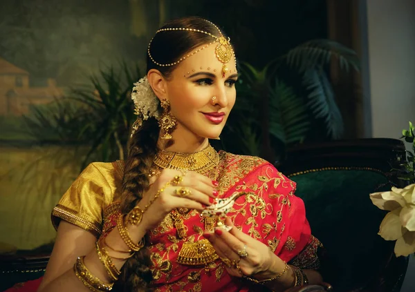 Portrait smiling of beautiful indian girl at home. Young woman model with golden jewelry set . — Stock Photo, Image