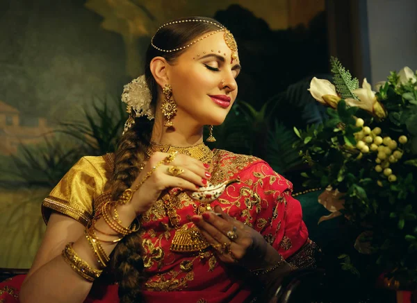 Portrait souriant de belle fille indienne à la maison. Jeune femme modèle avec ensemble de bijoux en or . — Photo