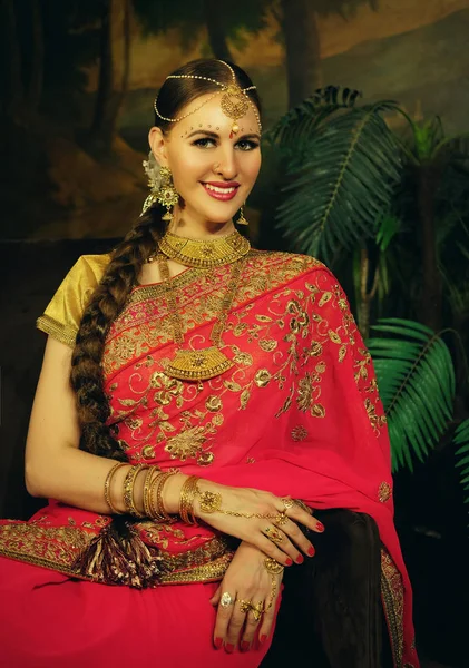 Porträtt leende av vacker indiansk flicka hemma. ung kvinna modell med gyllene smycken set . — Stockfoto