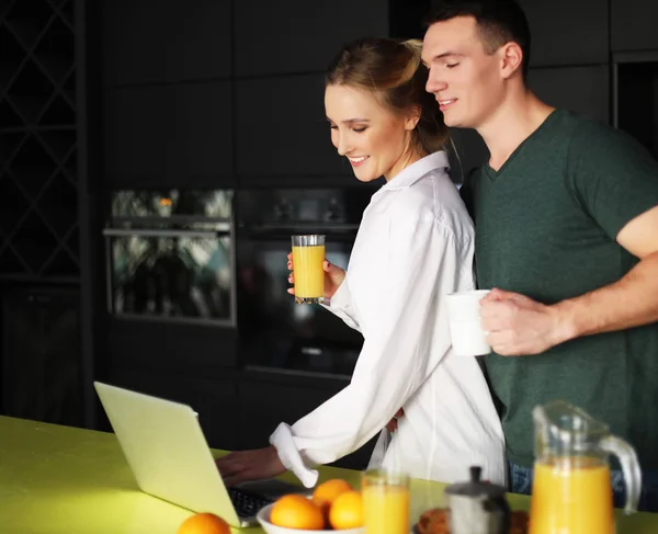 Fiatal pár otthon kávézás a konyhában, és dolgozik laptop számítógép — Stock Fotó