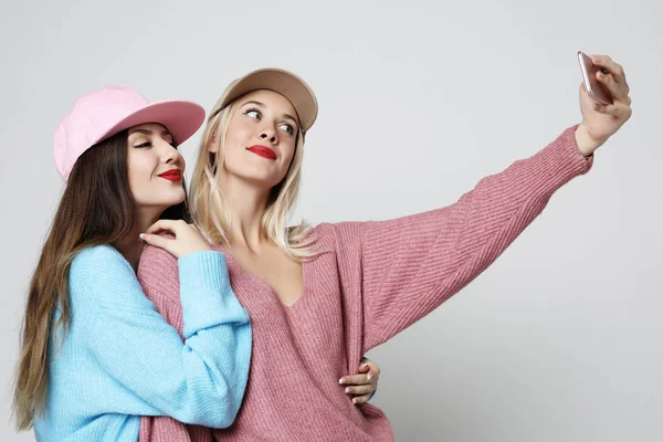 Dos amigas adolescentes en traje hipster hacen selfie en el teléfono inteligente . —  Fotos de Stock
