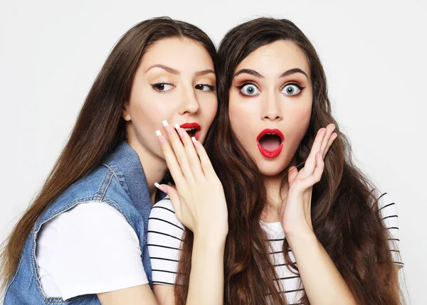 Retrato de dos jóvenes felices compartiendo secretos aislados sobre fondo blanco — Foto de Stock