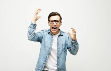  Mutlu genç yakışıklı adam el kol hareketi yapıyor ve ağzını kapalı tutuyor.