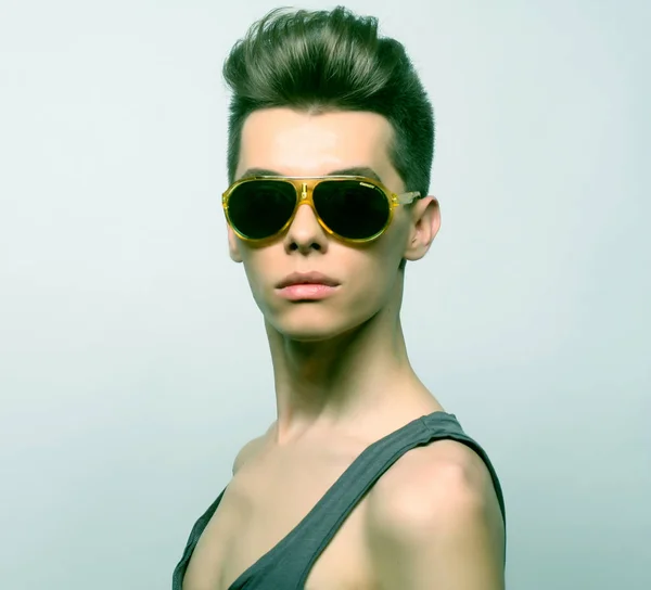 Den vackra unga mannen i solglasögon på en vit bakgrund. Modekoncept. — Stockfoto