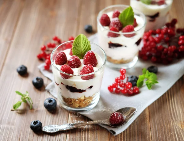Café da manhã saudável - iogurte com bagas frescas e muesli servido em jarra de vidro, em fundo de madeira — Fotografia de Stock