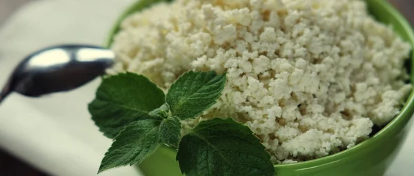 Fromage cottage à la menthe dans un bol vert sur une serviette blanche. Vue du dessus . — Photo