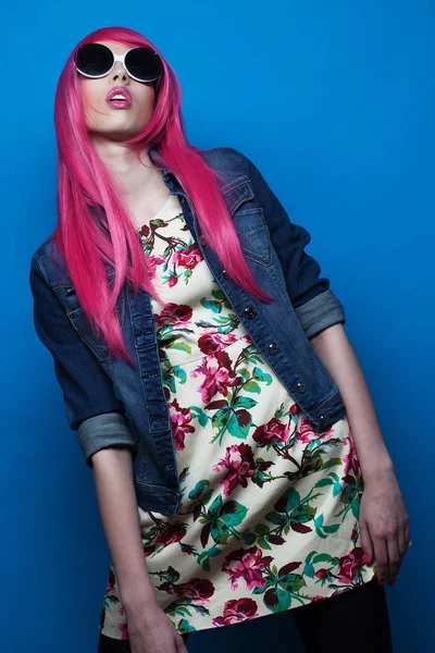 Fashion model with pink hair and big sunglasses over blue  background — Stock Photo, Image