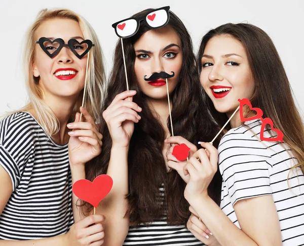 Tres mujeres jóvenes sosteniendo palos de fiesta de papel — Foto de Stock