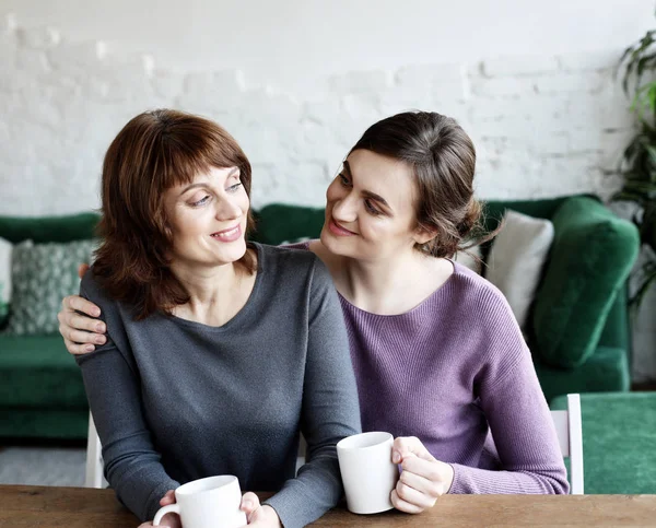 Vakker, moden mor og hennes voksne datter drikker kaffe. – stockfoto