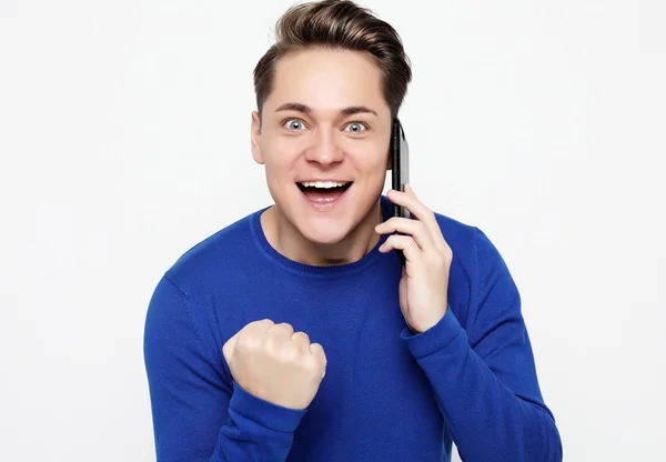 Feliz joven con camisa haciendo gestos y sonriendo mientras habla por teléfono móvil — Foto de Stock