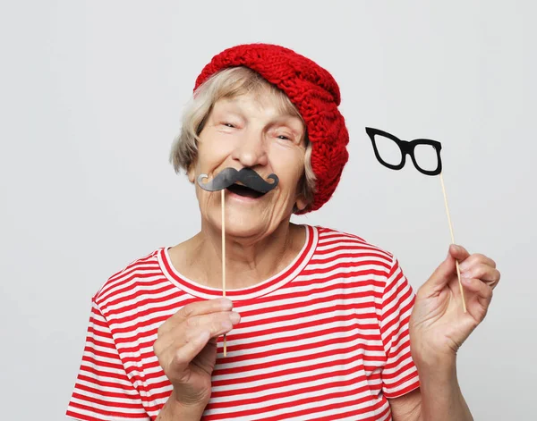 Lifestyle  and people concept: funny grandmother with fake mustache and glasses, laughs and prepares for  party — Stock Photo, Image