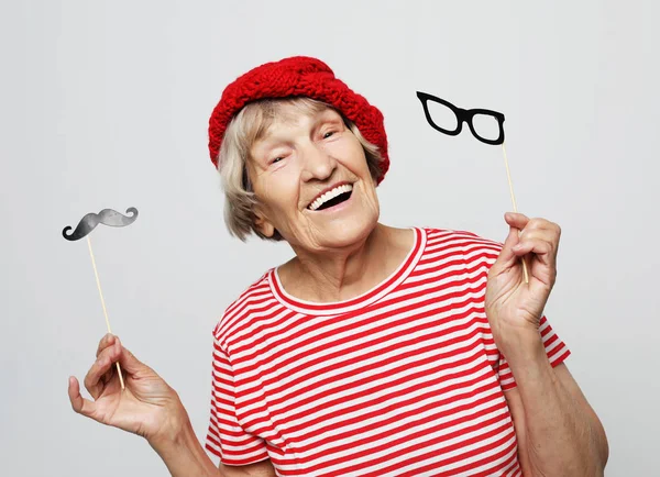 Estilo de vida y el concepto de la gente: abuela divertida con bigote falso y gafas, se ríe y se prepara para la fiesta — Foto de Stock