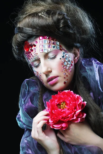 Mujer joven con maquillaje creativo sosteniendo flores —  Fotos de Stock