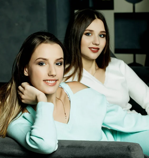 Två leende vänner sitter i soffan tittar på kameran i vardagsrummet hemma — Stockfoto