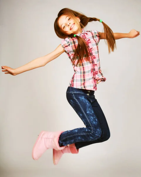 Little blond girl jumps on a gray background — Stock Photo, Image