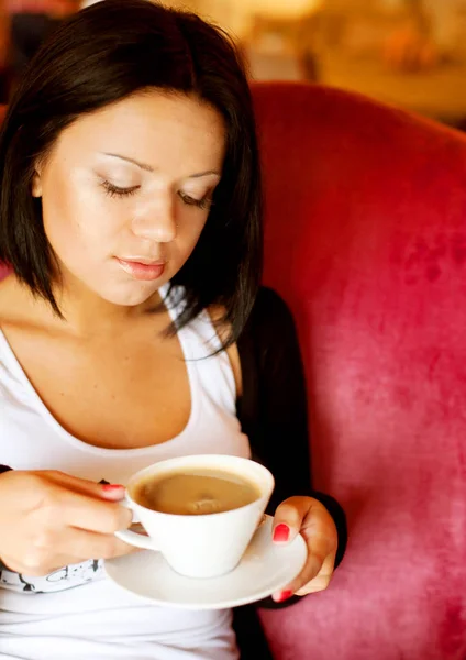 Jovem mulher sentada em um café bebendo café — Fotografia de Stock