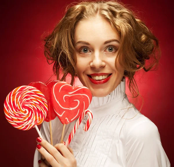 Mulher com caramelo coração sobre fundo vermelho — Fotografia de Stock