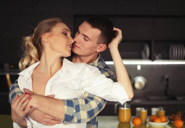 Lovely young couple standing and hugging on a kitchen at home — Stock Photo, Image