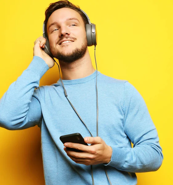 Fiatal férfi fülhallgatóval és mobiltelefonnal. — Stock Fotó