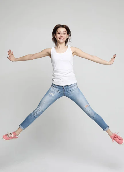 Sonriente joven mujer saltando en el aire sobre fondo blanco —  Fotos de Stock