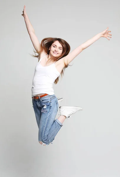 Sorrindo jovem mulher pulando no ar sobre fundo branco — Fotografia de Stock