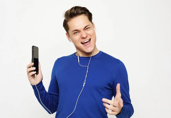 Joven guapo hombre en blanco estudio fondo escuchar música en los auriculares — Foto de Stock