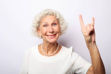 Yaşlı mutlu kadın başparmağını kaldırıyor ve kameraya bakıyor.