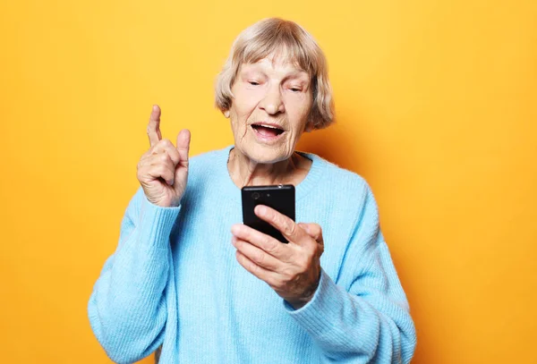 Mulher velha vestindo camisola azul falando no telefone celular — Fotografia de Stock