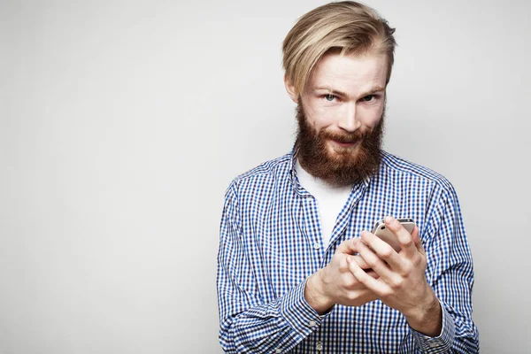 Nahaufnahme eines jungen bärtigen Mannes, der auf den Bildschirm seines Smartphones blickt — Stockfoto