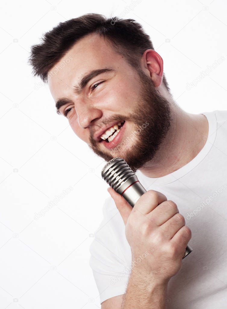 young bearded man in white shirt singing in microphone