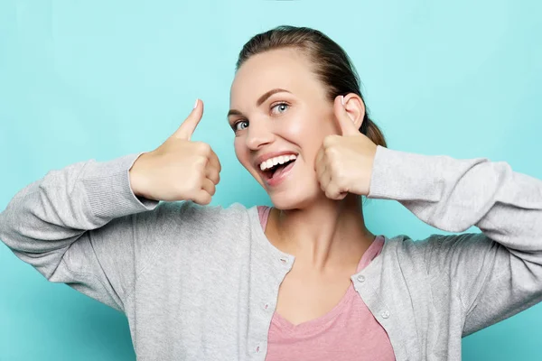 Happy young caucasian female making thumb up sign and smiling cheerfully