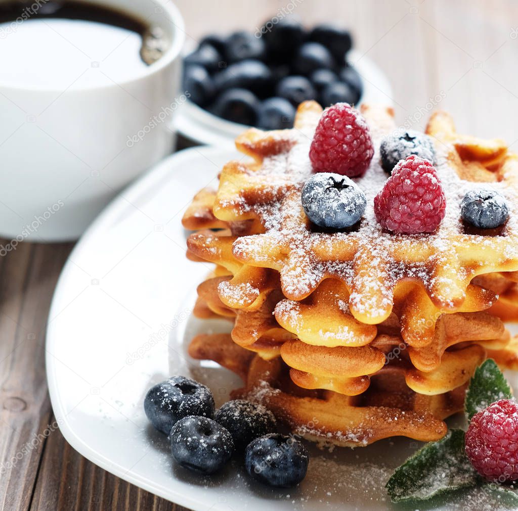 Waffles with  berries on a white plate and coffee, close up.