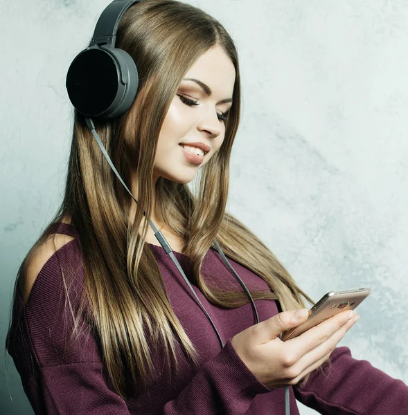 İnsanlar ve teknoloji kavramı - kulaklıklı mutlu kadın akıllı telefondan müzik dinliyor.