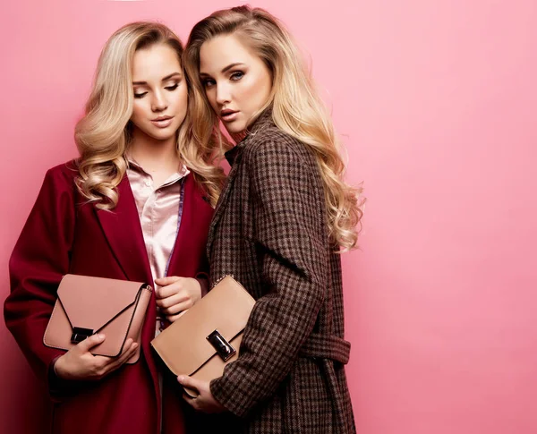 Dos mujeres jóvenes y dulces posando con ropa bonita, abrigo, bolso. Hermanas, gemelas. Primavera moda foto . —  Fotos de Stock