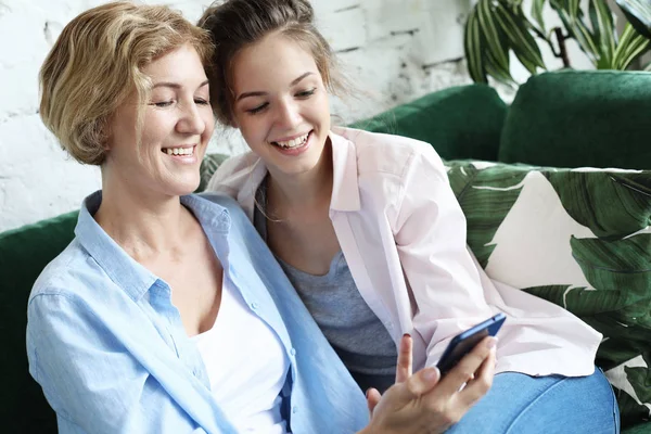 Family and technology. Aged woman and her adult daughter using smartphone at home. — Stock Photo, Image