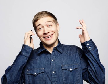 Smartphone ile konuşmak ve kameraya bakarak gülümseyen genç adam